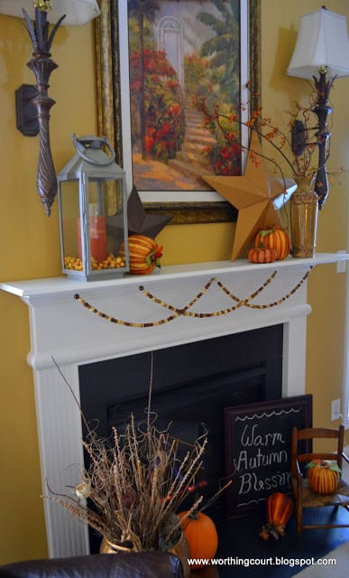 Faux pumpkins, a lantern, metal stars and wooden beads make up the Fall decor on this mantle