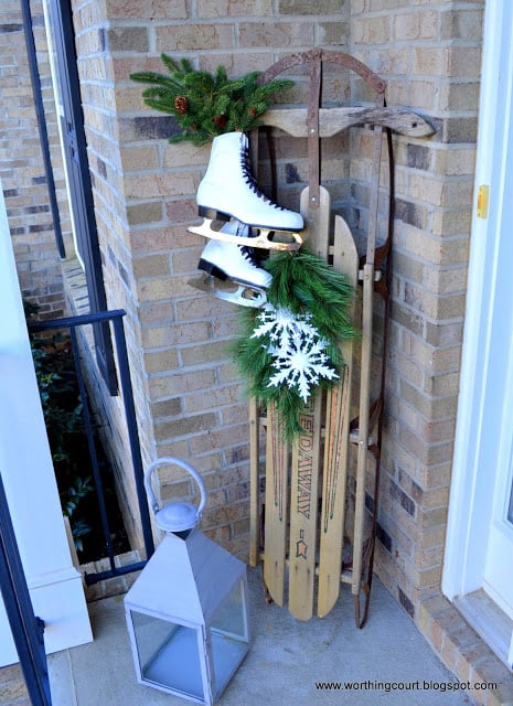 Worthing Court: Winter front porch with a vintage sled, ice skates, greenery and burlap snowman wreath
