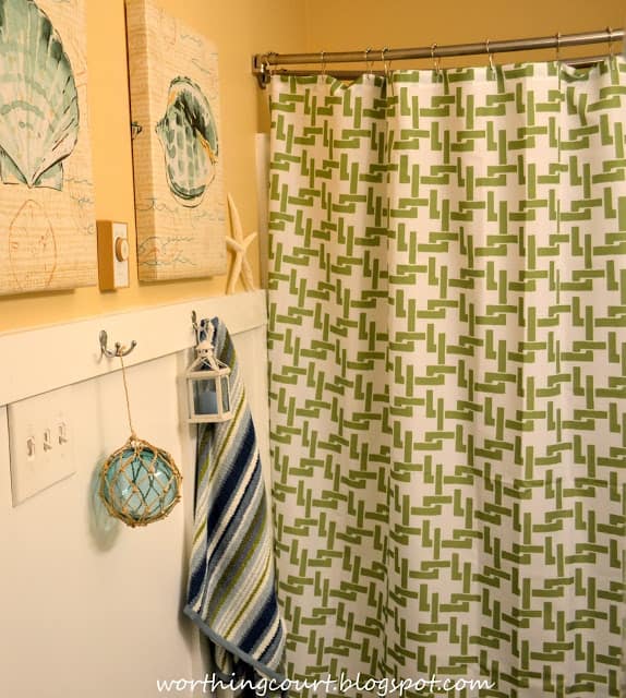 There is a green and white shower curtain hanging in the bathroom.