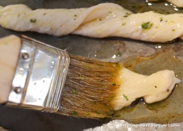 Brushing the herbs onto the breadstick dough.