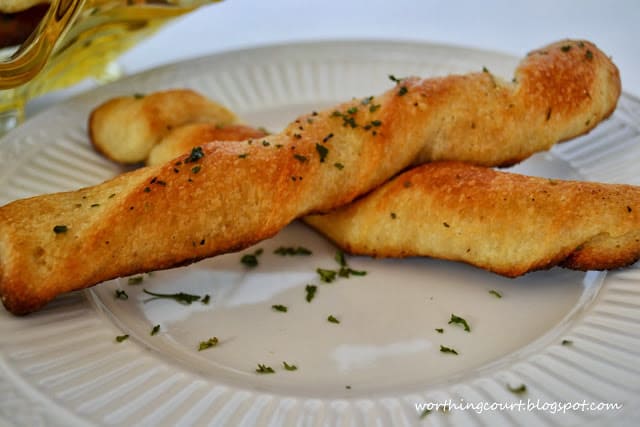 Two breadsticks on a white plate.