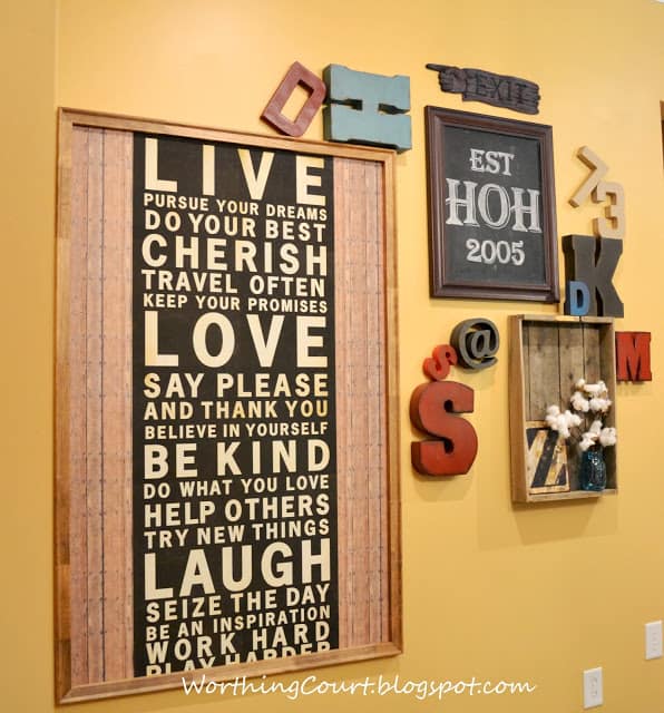 A yellow wall with typography framed pictures on it.