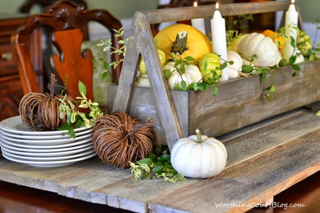 Worthing Court: Wooden tool box filled with yellow and white pumpkins and fresh greenery. The aged wood makes a great base for the centerpiece.