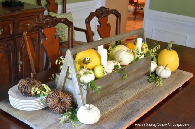 Worthing Court: Wooden tool box filled with yellow and white pumpkins and fresh greenery. The aged wood makes a great base for the centerpiece.