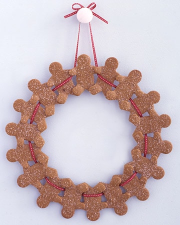 Gingerbread men formed into a wreath with red and white ribbon hanging from a hook.