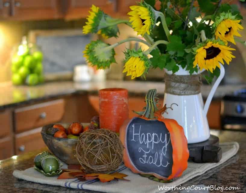 Fall Kitchen Island Vignette filled with flowers, a candle and a faux pumpkin.