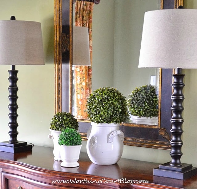An easy spring dining room vignette made up of various sized urns topped with faux greenery orbs