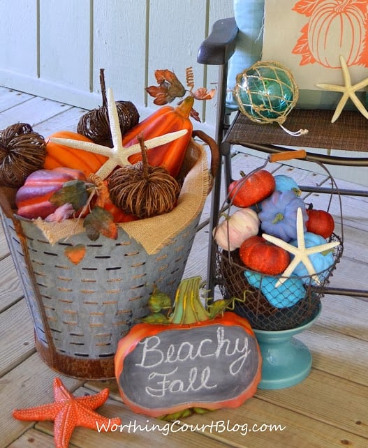 A galvanized bucket filled with pumpkins and fall items.