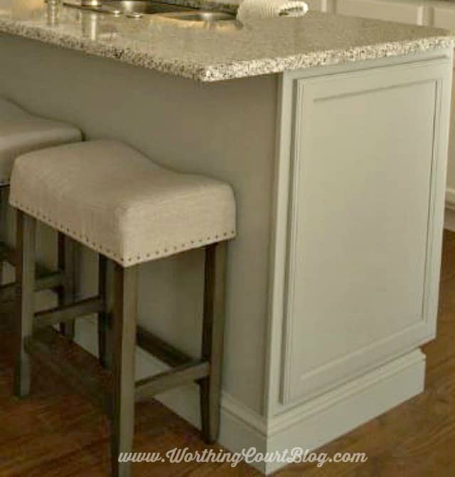 Add dummy cabinet doors to the end of an island and wrap it matching baseboard to make it look like a piece of furniture.