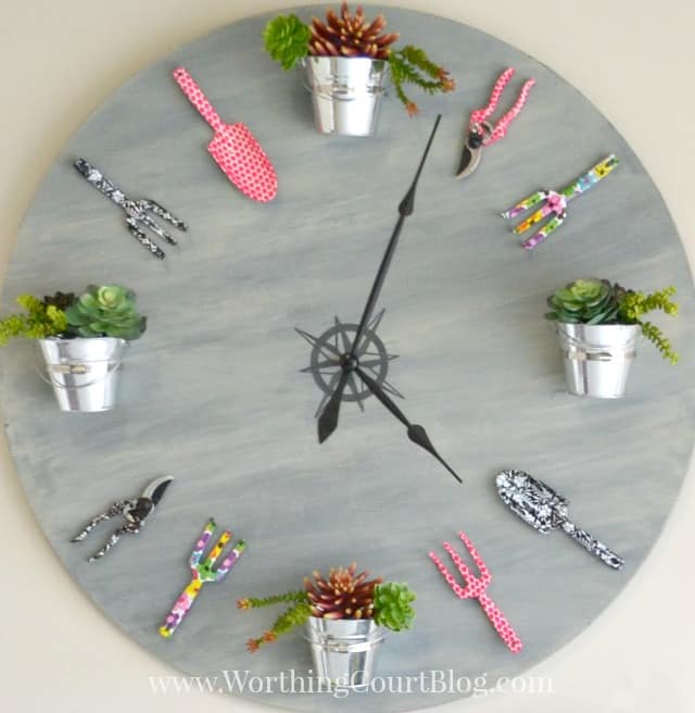 huge faux wall clock made with an old tabletop and decorative gardening tools