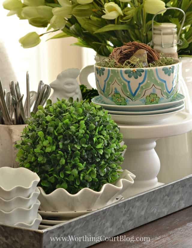 A round topiary is sitting in a white dish on the table.