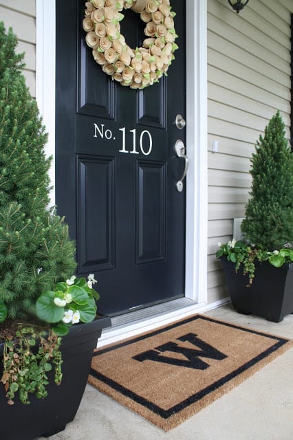 A number decal on a dark front door with a floral wreath.