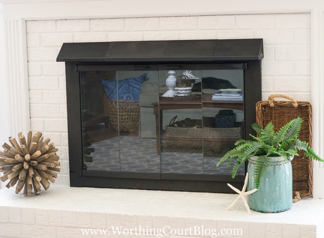 The lower mantel with a spiky ball, blue potted fern plant, wicker basket and a starfish.