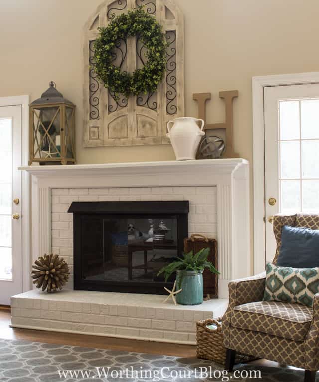 Red brick fireplace with brown trim painted white and brass fireplace screen painted with black high temp spray paint