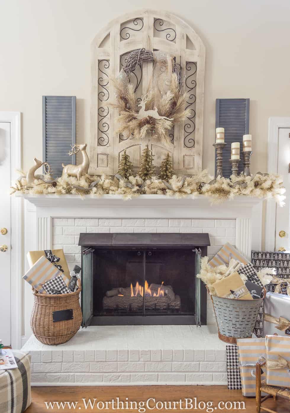 A white fireplace with baskets flanking the sides of it and a mantel decorated for Christmas.
