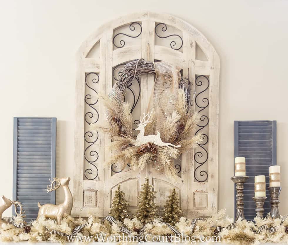A rustic window frame with a Christmas wreath and deer and candlesticks on the mantel.