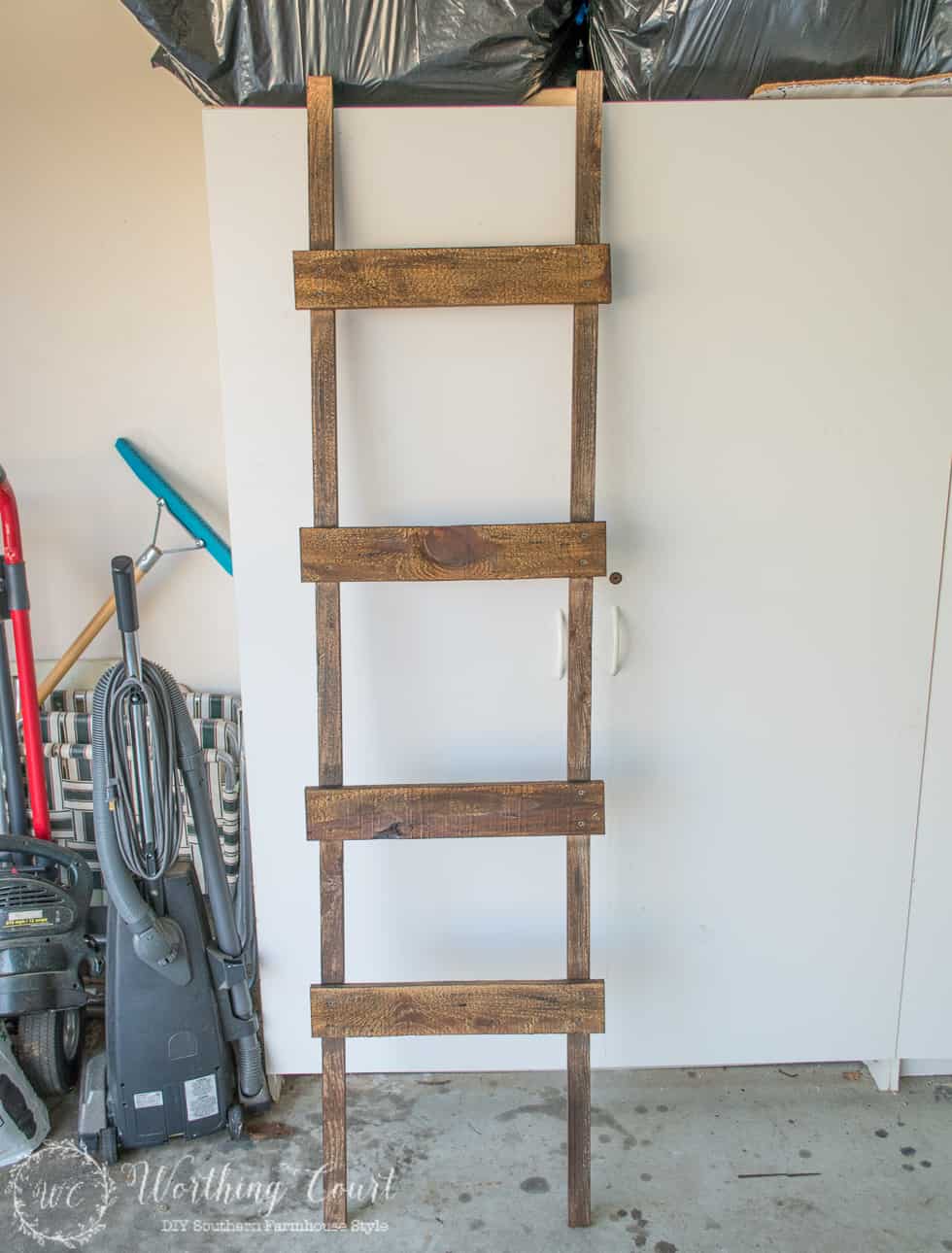 The distressed painted ladder in the garage leaning against the wall.