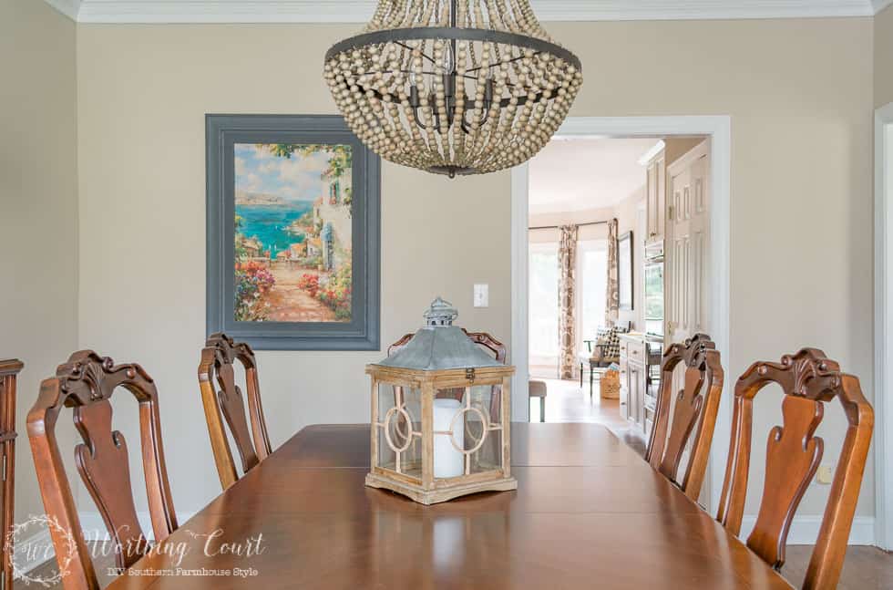 A wooden dining room table with a beaded chandelier above it.