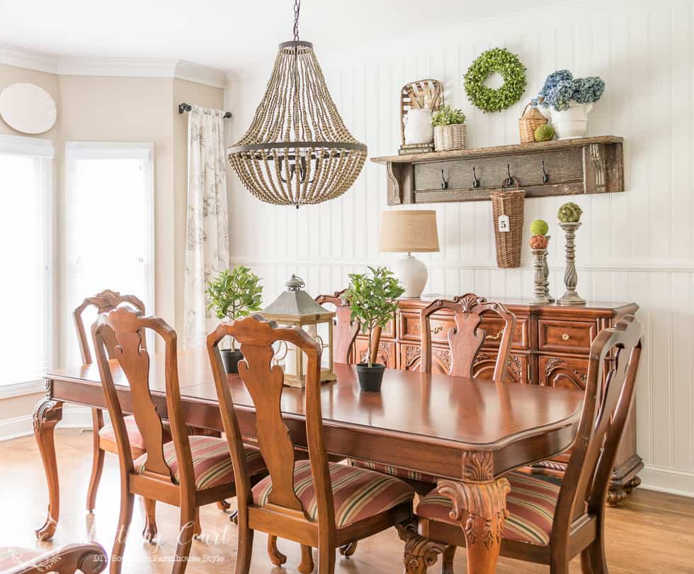 Combining farmhouse touches with traditional dining room furniture and a large beaded chandelier above the table.