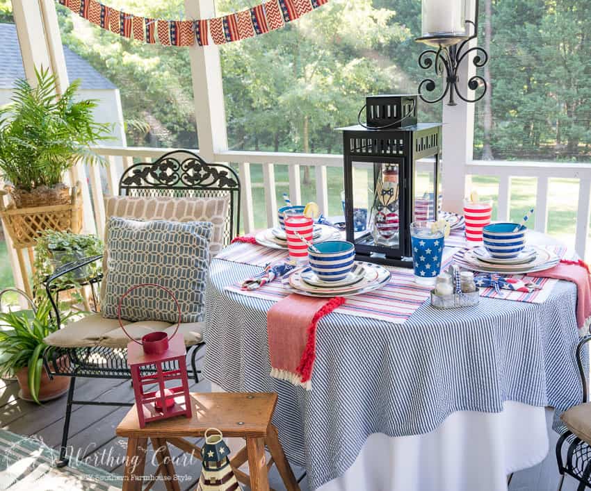 A patriotic table setting on a farmhouse porch filled with loads of red, white and blue vintage Americana patriotic decorating ideas for Memorial Day, Flag Day and July 4th.