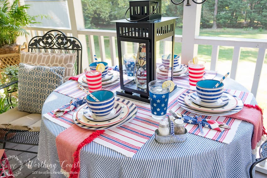 A patriotic table setting on a farmhouse porch filled with loads of red, white and blue vintage Americana patriotic decorating ideas for Memorial Day, Flag Day and July 4th.