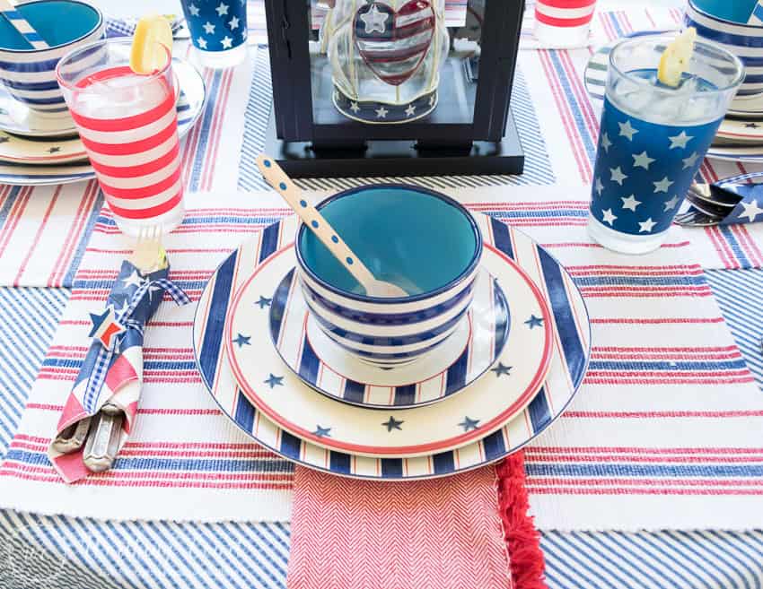 A patriotic table setting on a farmhouse porch filled with loads of red, white and blue vintage Americana patriotic decorating ideas for Memorial Day, Flag Day and July 4th.