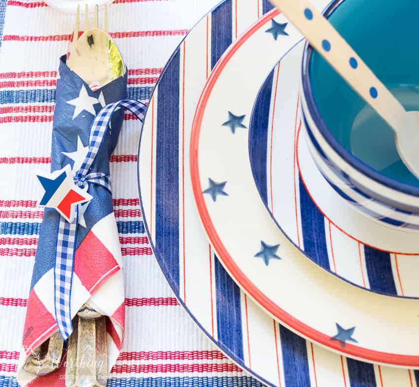 A patriotic table setting on a farmhouse porch filled with loads of red, white and blue vintage Americana patriotic decorating ideas for Memorial Day, Flag Day and July 4th.