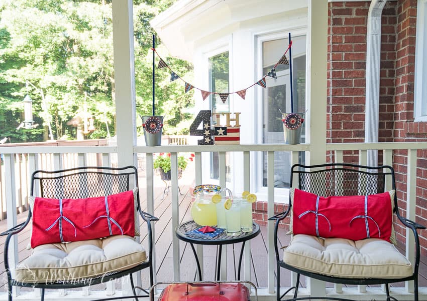 A farmhouse porch filled with loads of red, white and blue vintage Americana patriotic decorating ideas for Memorial Day, Flag Day and July 4th.