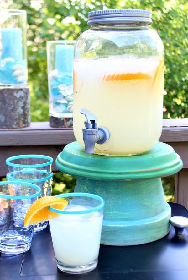 DIY drink dispenser stand with glasses of lemonade in front of it.