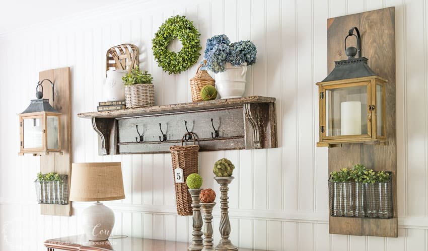 A small green wreath on the wall above the wooden shelf.