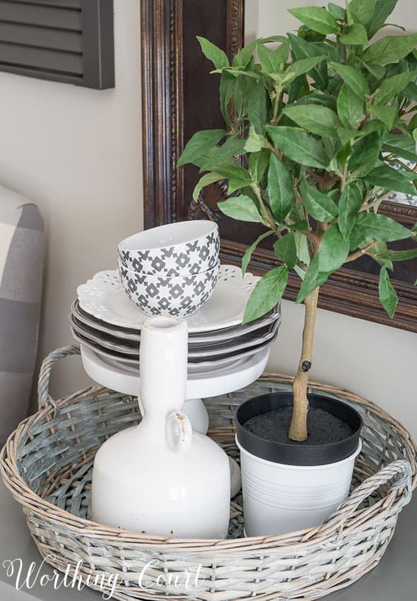 Farmhouse Dining Room Makeover - vignette with stacked dishes on a pedestal inside a round wicker tray