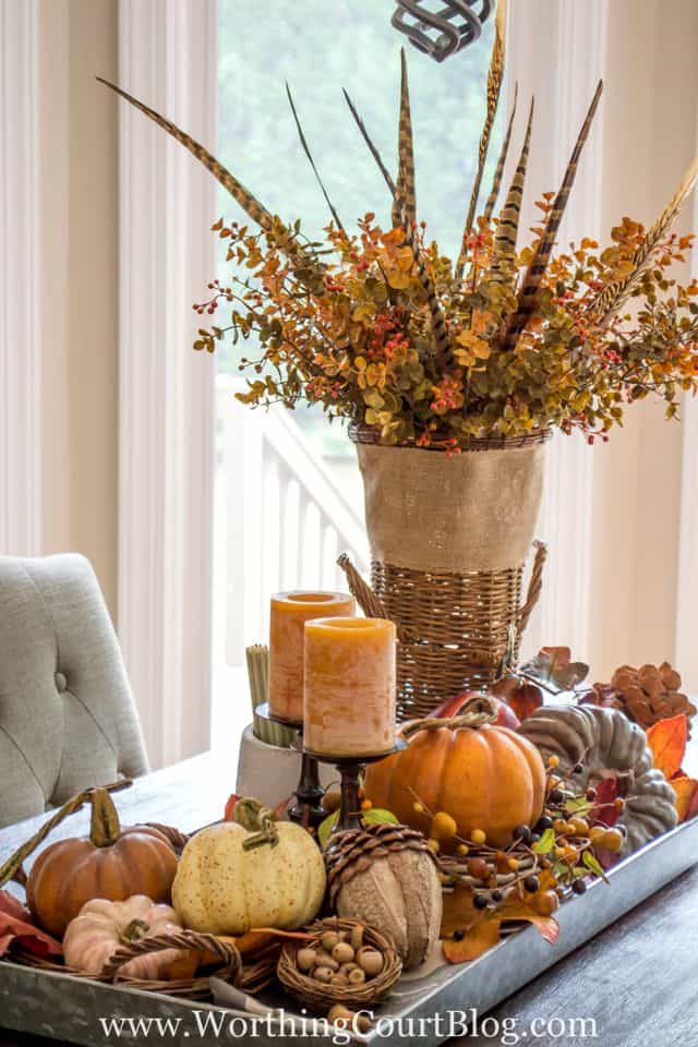 Farmhouse Fall Table Centerpiece in a galvanized tray, pops or orange and amber with pumpkins and candles.