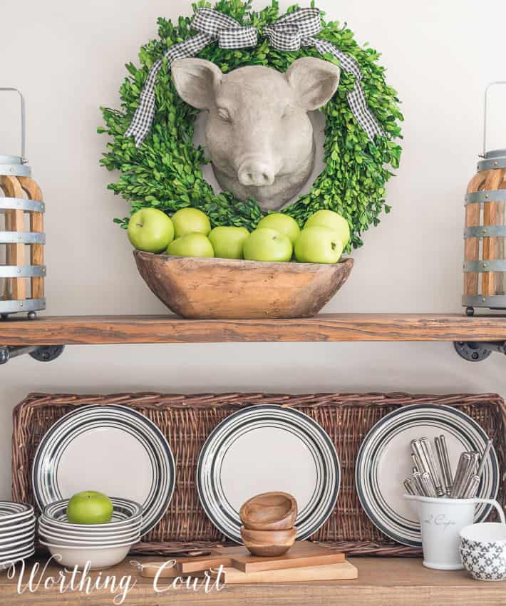 Faux pig head wall hanging above open rustic farmhouse shelves