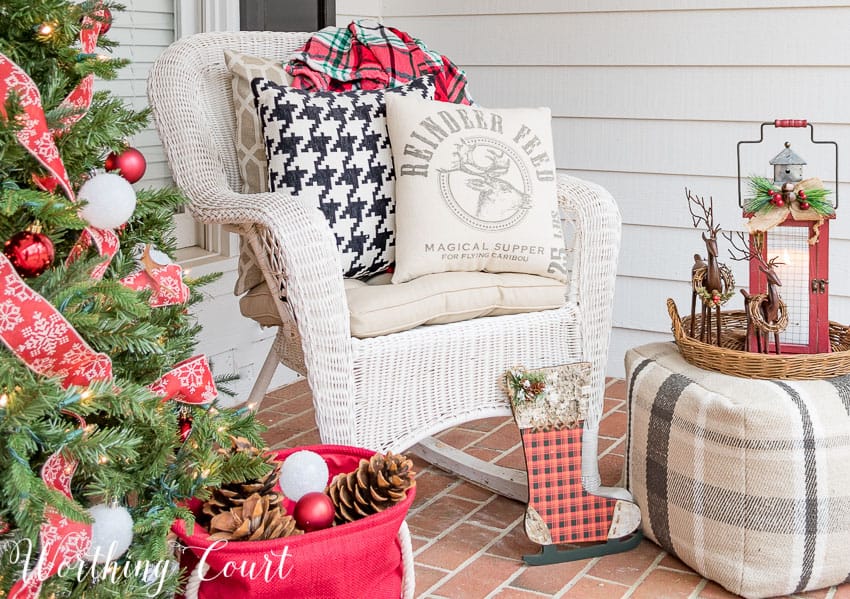 A fabric ottoman holding a wicker tray with reindeers is on the porch.