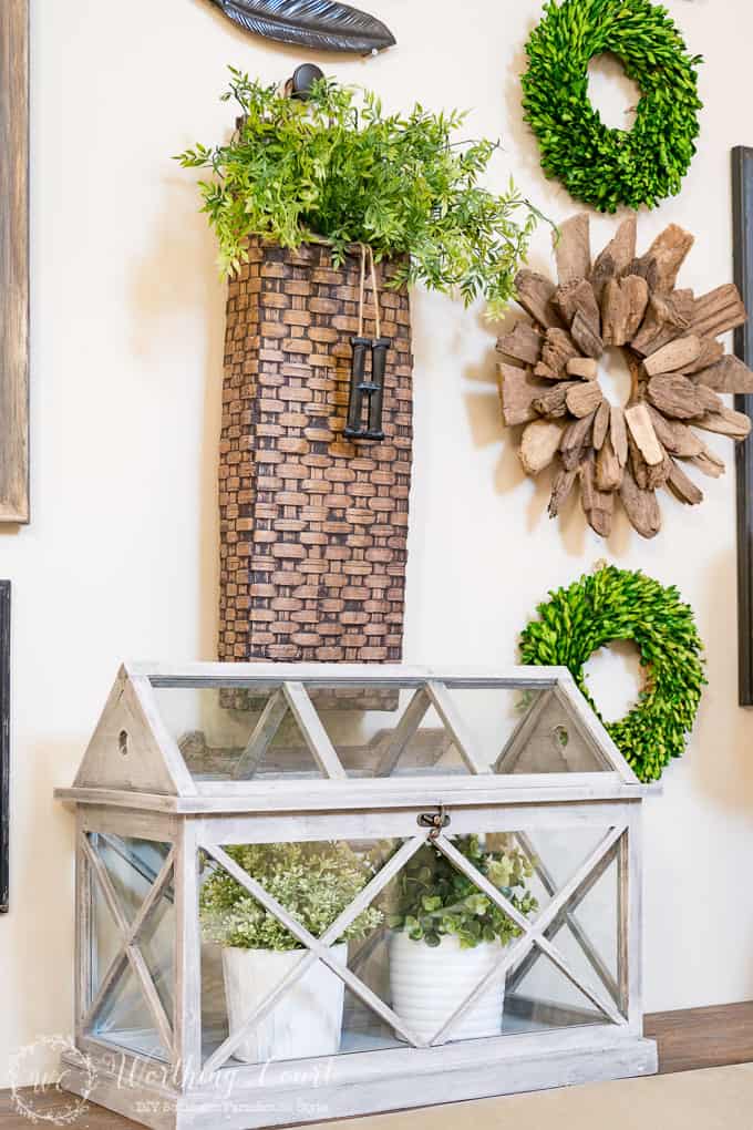 Spring family room decor with a bright green wreath, and plants underneath a greenhouse.