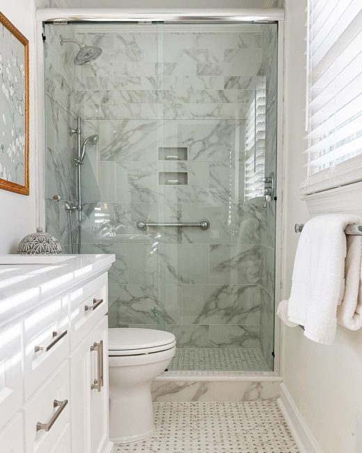 bathroom with marble-look tile shower and a white vanity