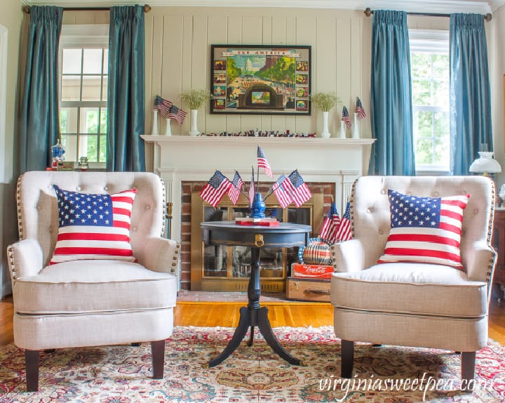 two white chairs in front on a white fireplace with patriotic decor