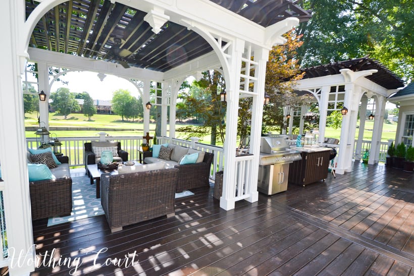 A large deck with beige furniture and a bbq in the middle.