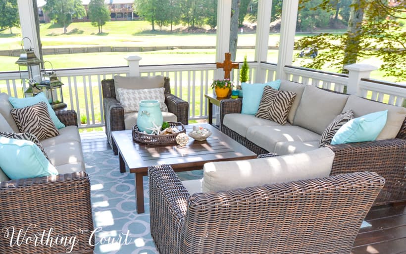 There is a small wooden table in the middle of the furniture on the deck.