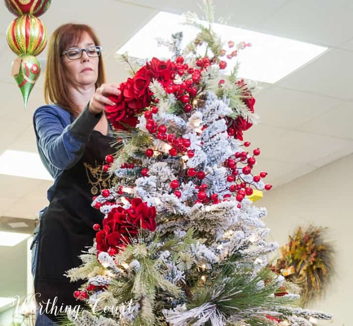 A woman putting Christmas tree topper using red roses.