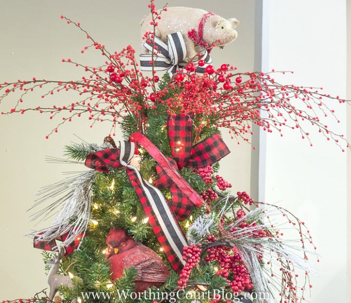 Christmas tree topper with red berries and ribbon and a piglet.