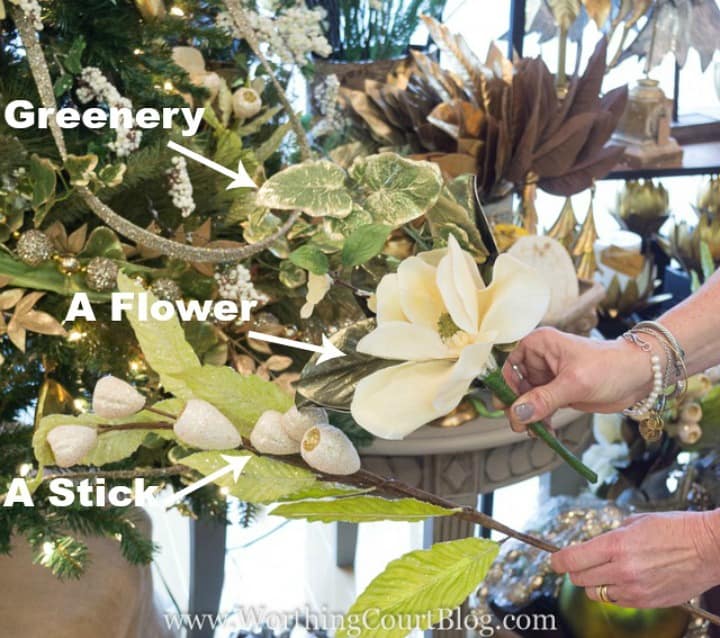 Holding a white large flower to apply to the tree.