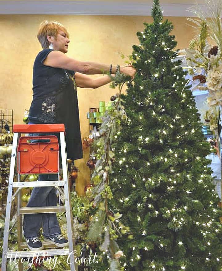 Designer adding garland to a Christmas tree.