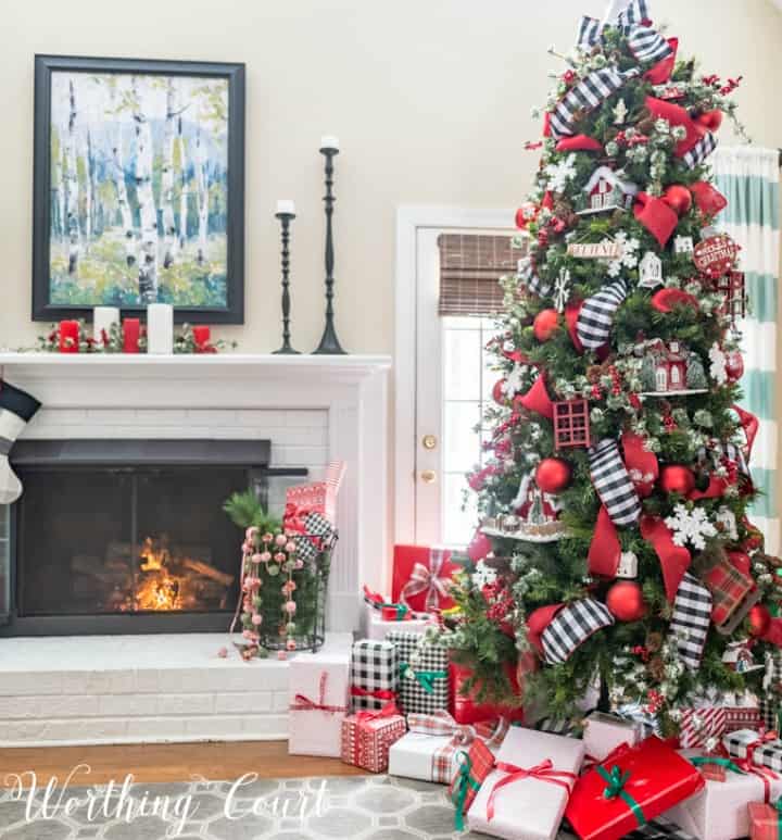 Christmas tree decorating with red ornaments and black and white ribbon.