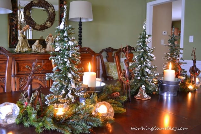 Christmas centerpiece with mini flocked Christmas trees and evergreen and lights.