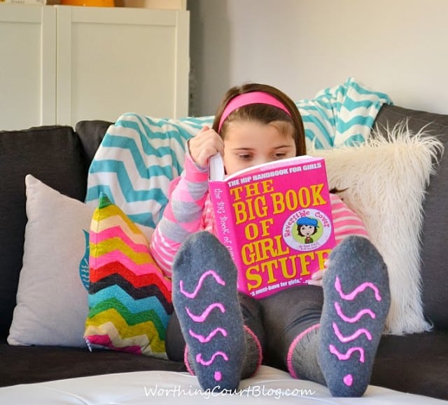 A little girl reading a book in her no slip socks.