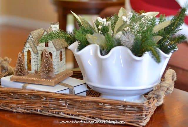 A fluted bowl filled with faux greenery, wintery leaves and berries.