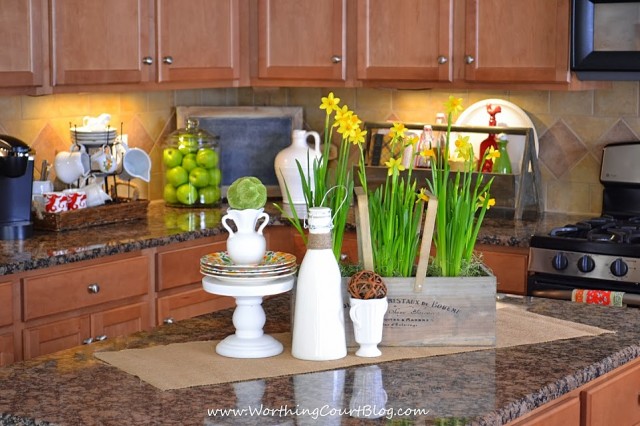 Easy and cheery 5 minute Spring vignette on a kitchen island with daffodils and other natural elements.
