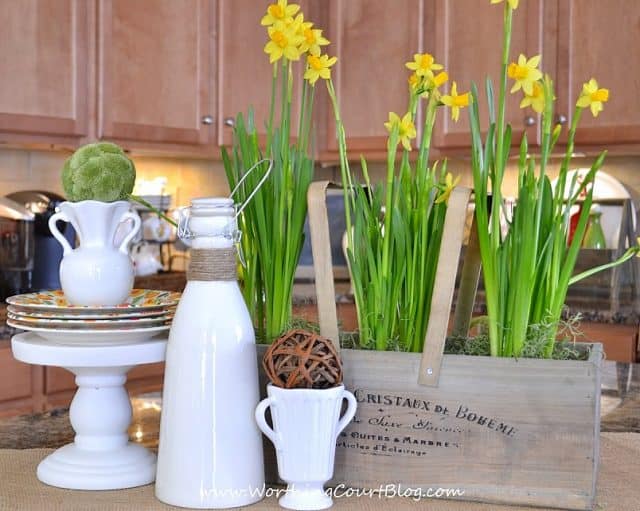 Brown cabinets in the kitchen with yellow daffodils on the island.