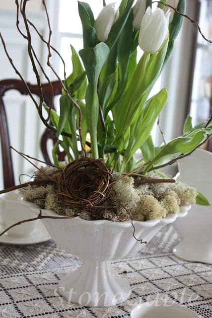 A white fluted bowl filled with spring flowers, twigs, a bird nest and bits of reindeer moss makes a lovely neutral centerpiece.